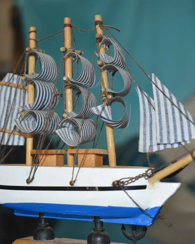 Detail stěžňů malého dřevěného modelu lodi s ubranými plachtami a lany vedenými k bokům trupu